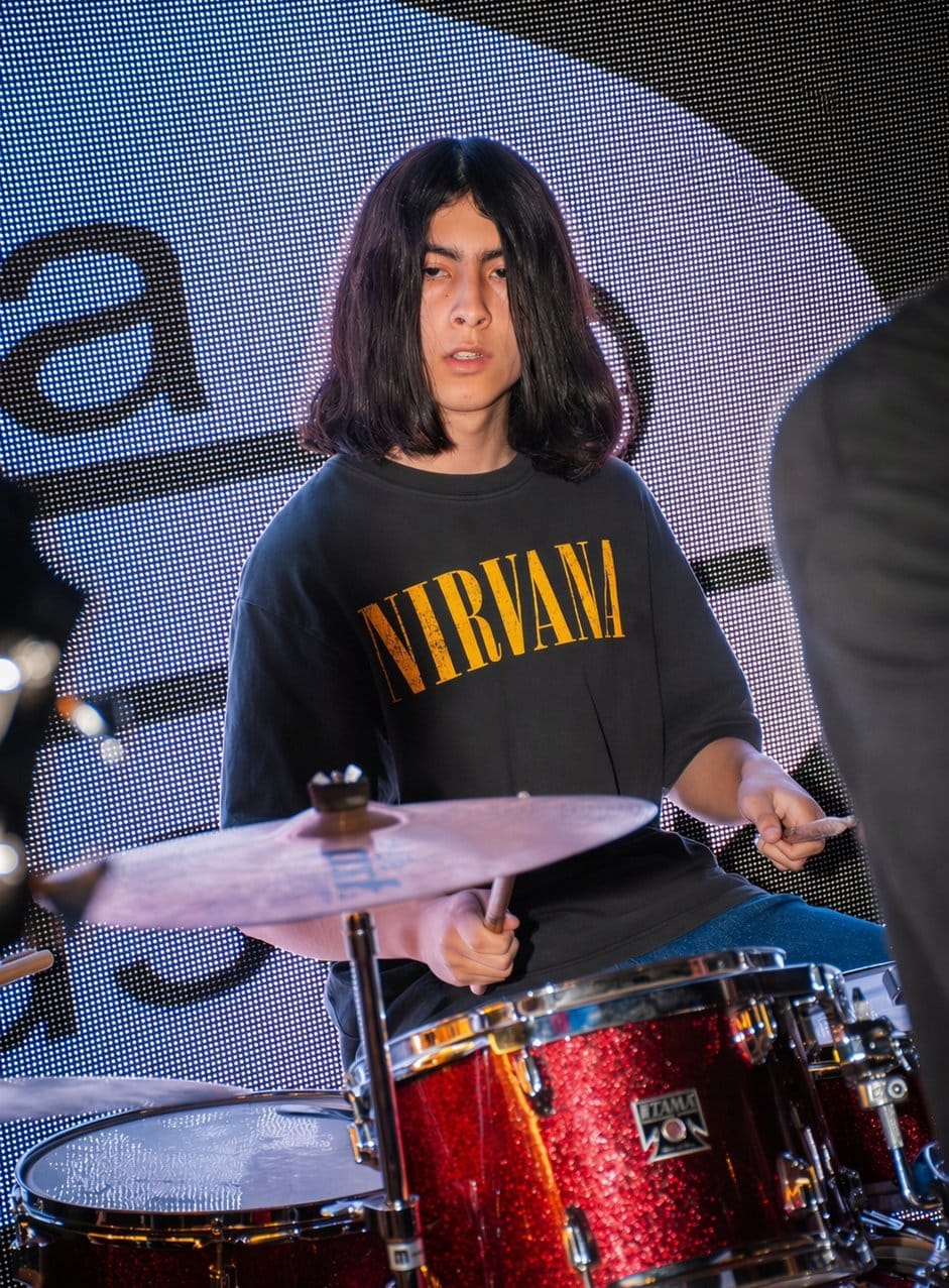 Alumno tocando batería en presentación en vivo